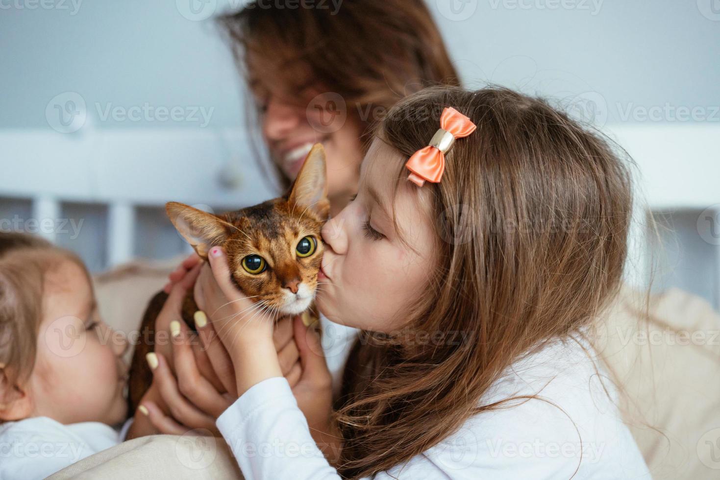 Happy mother and two daughters smiling hugs in bed photo