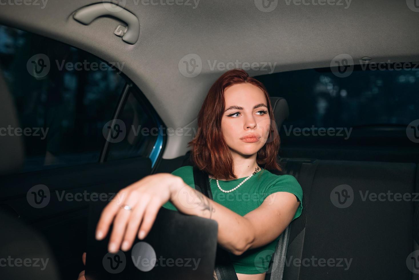 Beautiful woman is using laptop while sitting on back seat photo