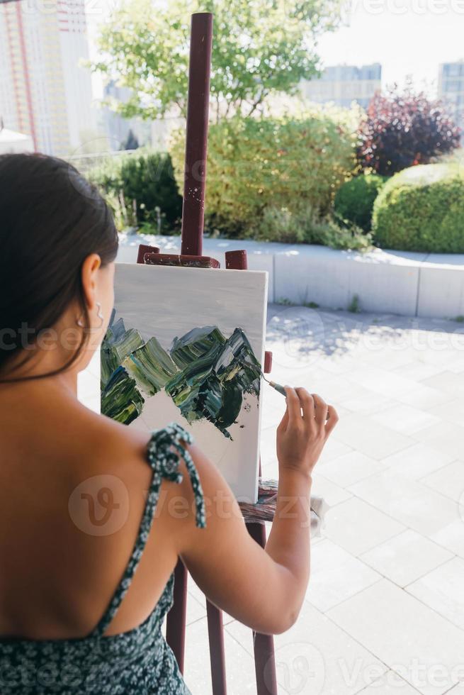 Young woman artist paints with a spatula on the canvas photo