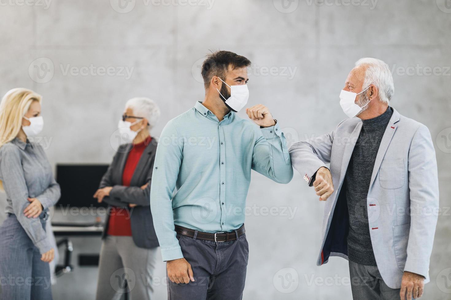 dos hombres de negocios saludando con codos golpeados durante la pandemia del coronavirus en la oficina foto