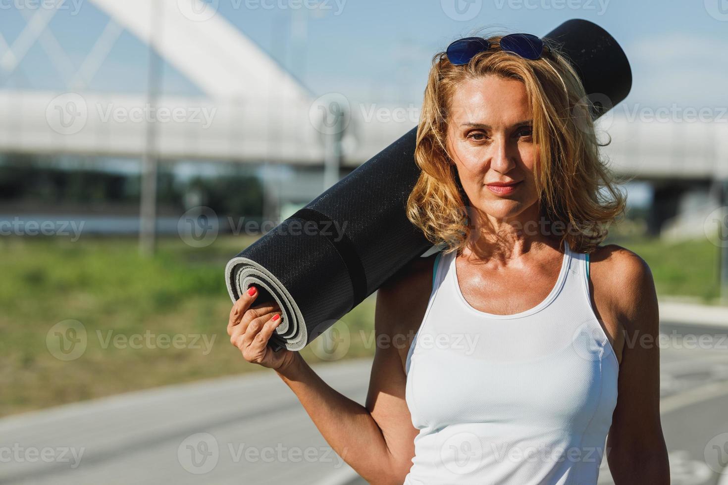 Portrait Of Woman With Rolled Up Exercise Mat photo