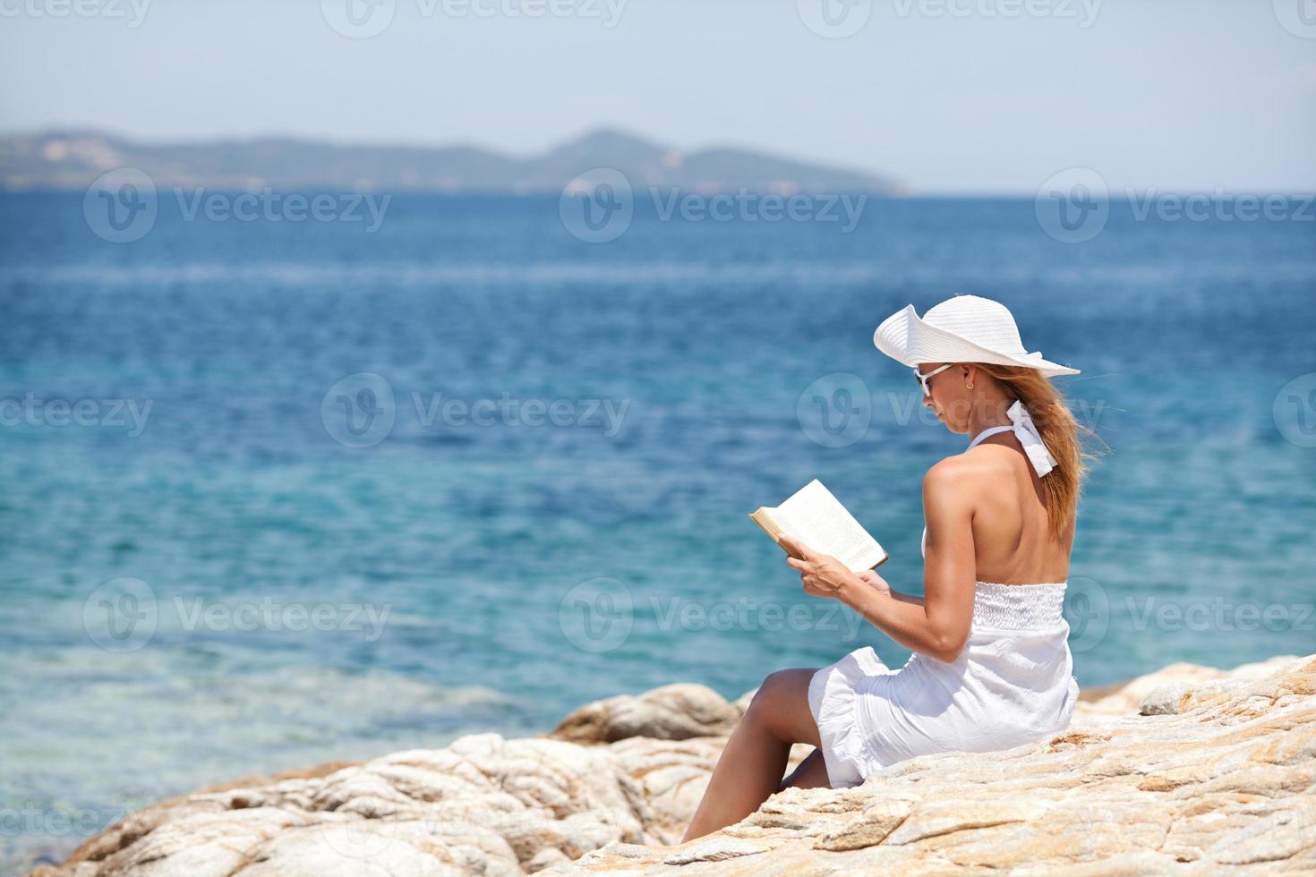 Young Woman Reading Book On The Beach photo