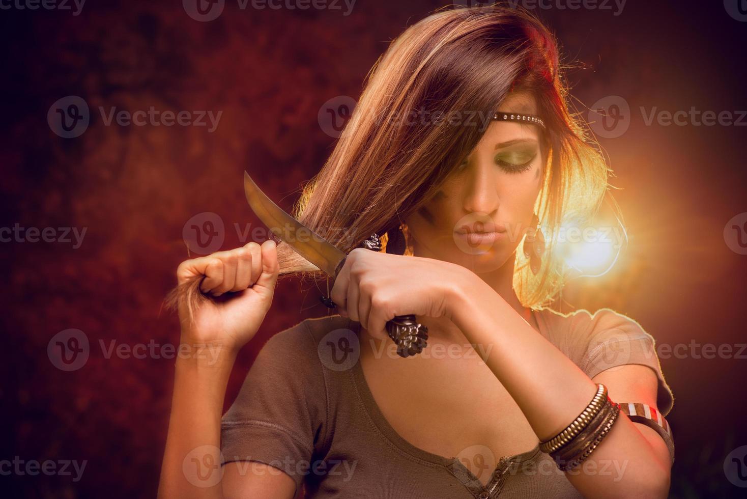 mujer cortando cabello con cuchillo de combate foto
