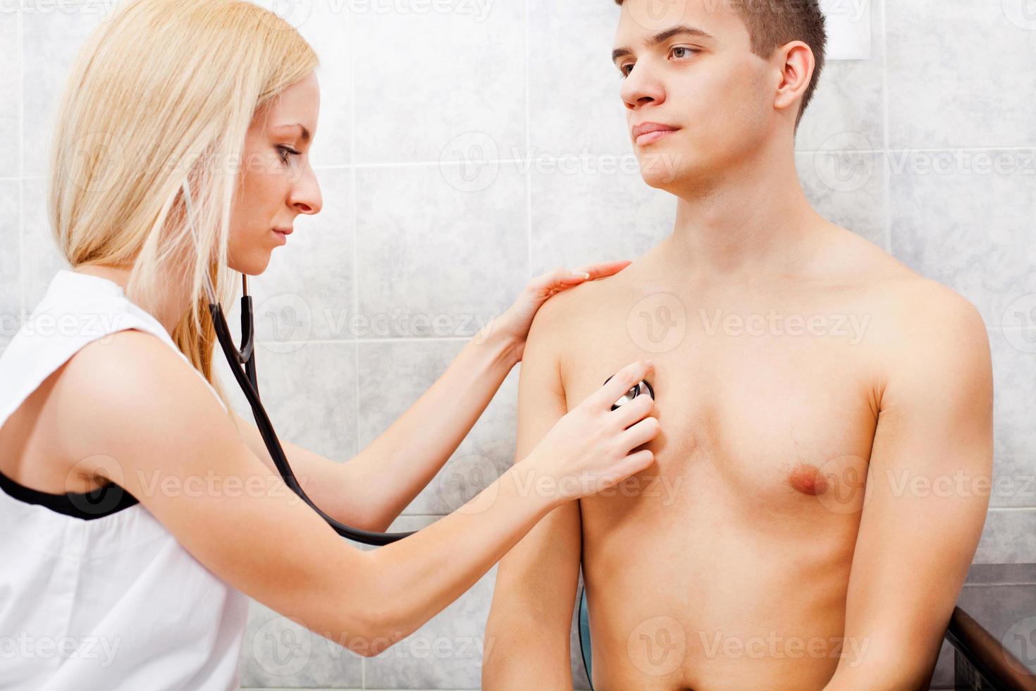 Examining young man with stethoscope photo