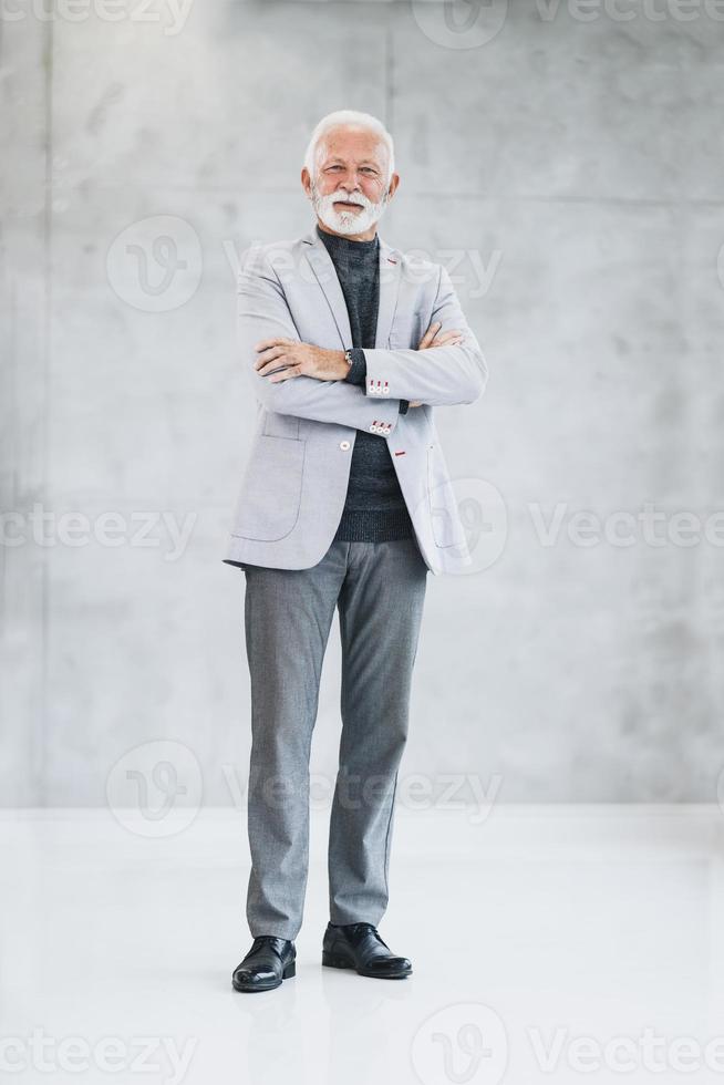 A Senior Business Man Standing With Crossed Arms And Looking At Camera photo