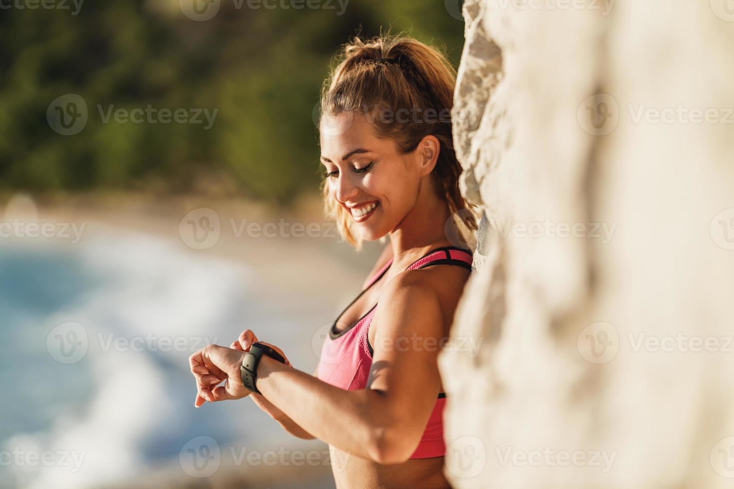 Woman Checking Progress And Looking Heart Rate On Smart Watch During Training Near The Sea photo