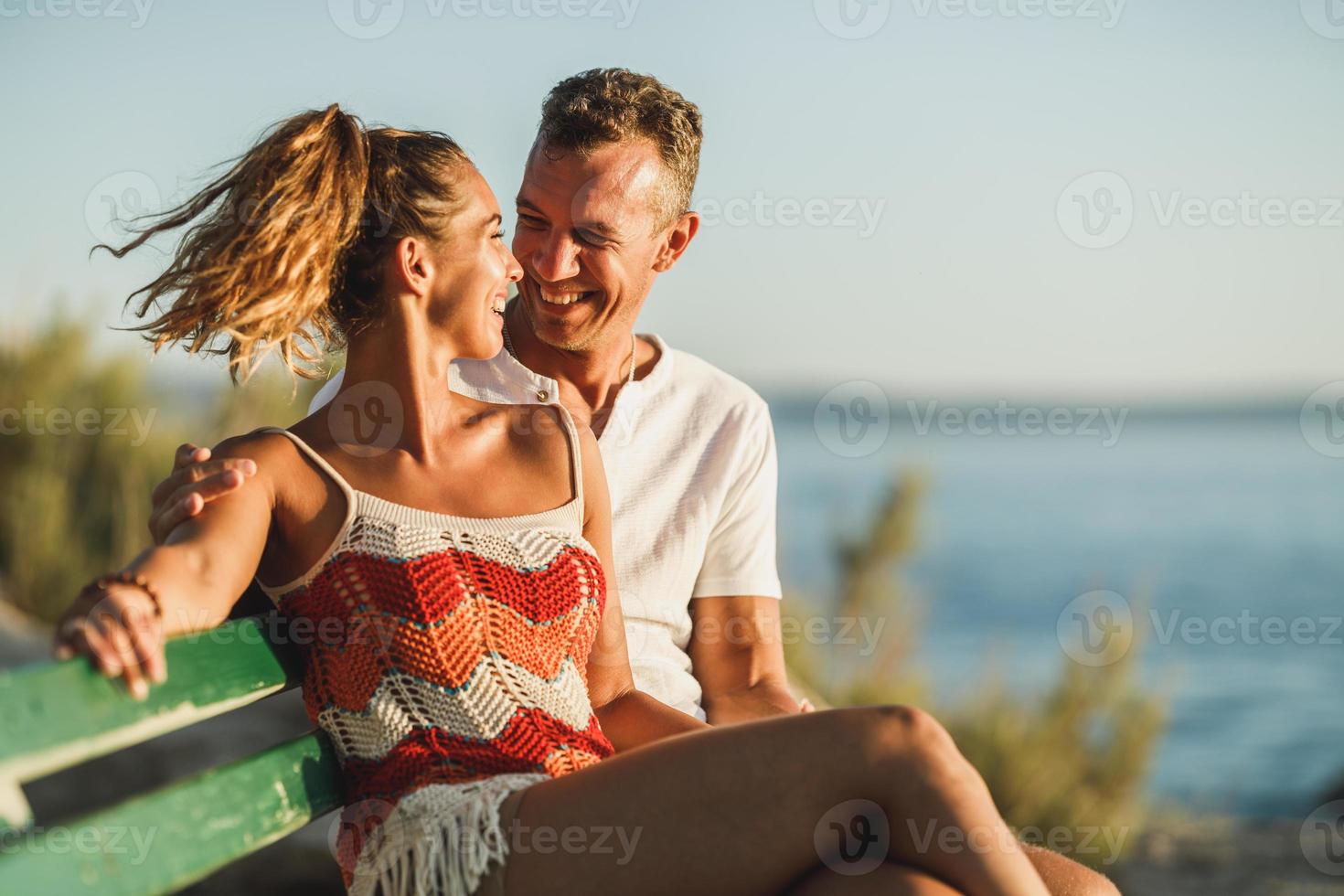 Couple Sitting On Bench And Enjoying Time On A Vacation Near The Beach photo