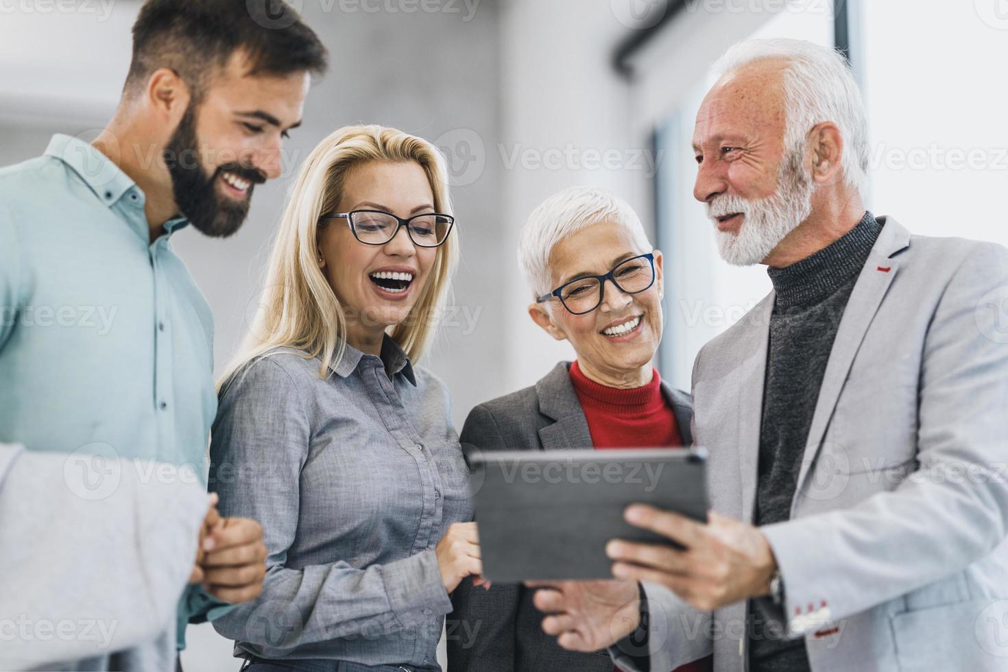 un grupo de empresarios confiados que usan una tableta digital durante una reunión en la oficina foto