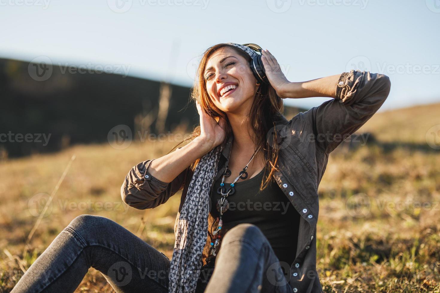 mujer sentada en el prado y escuchando música con auriculares foto