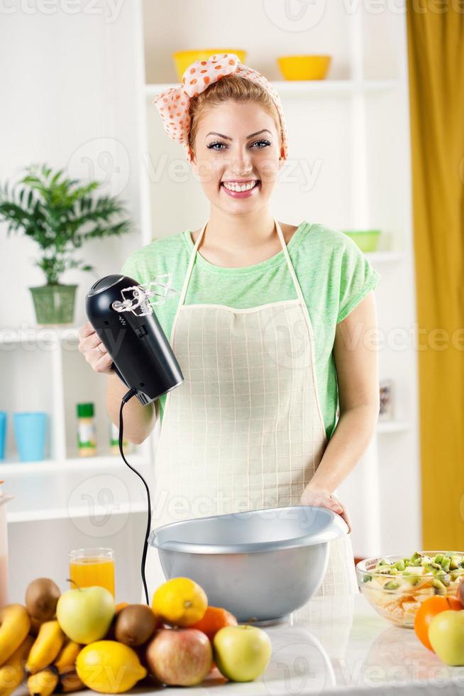 mujer joven con batidora eléctrica foto