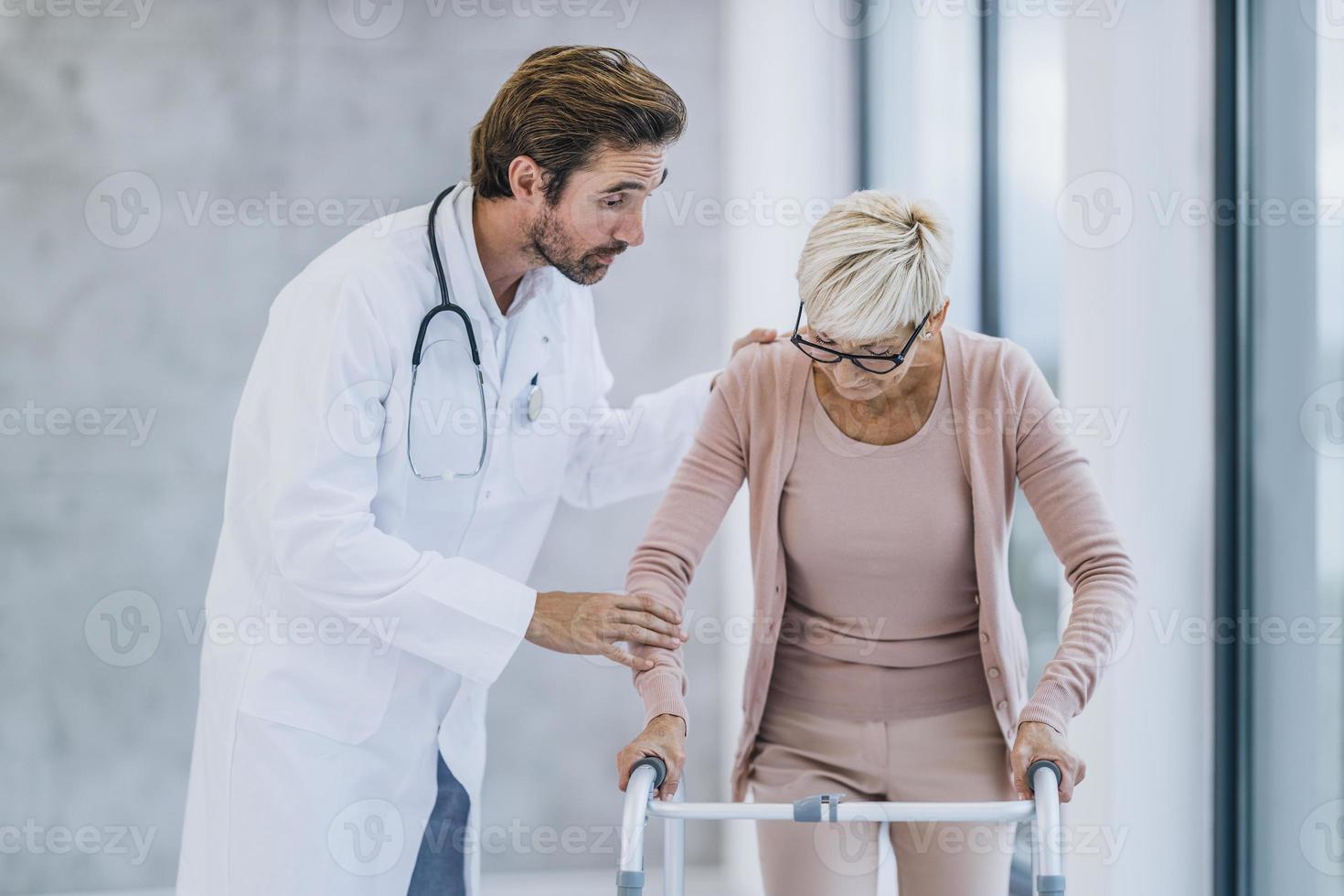 Senior Woman Learns To Walk With Mobility Walker With The Assistance Of A Doctor photo