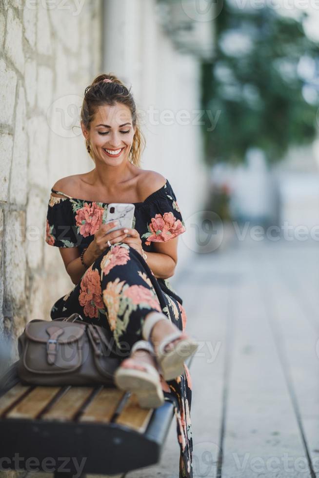Woman Using A Smartphone And Surfing The Net While Sitting On A Bench In The Mediterranean City photo