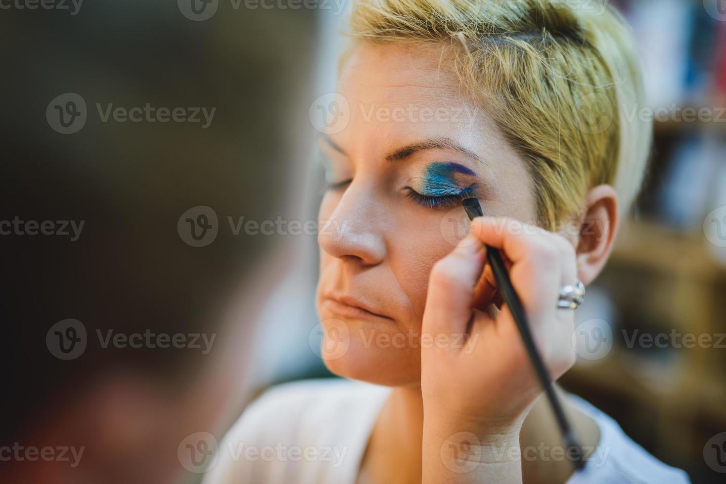 Makeup Artist Applying Eyeshadow On A Girl photo