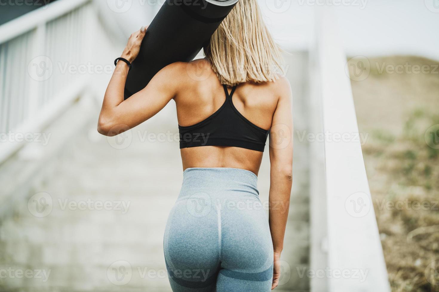 Woman Holding Rolled Up Yoga Mat And Preparing For Training Outdoor photo