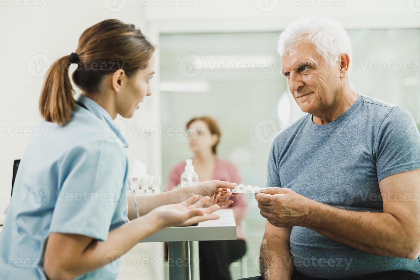 Caring Nurse Talking To Senior Man At Hospital Waiting Room photo