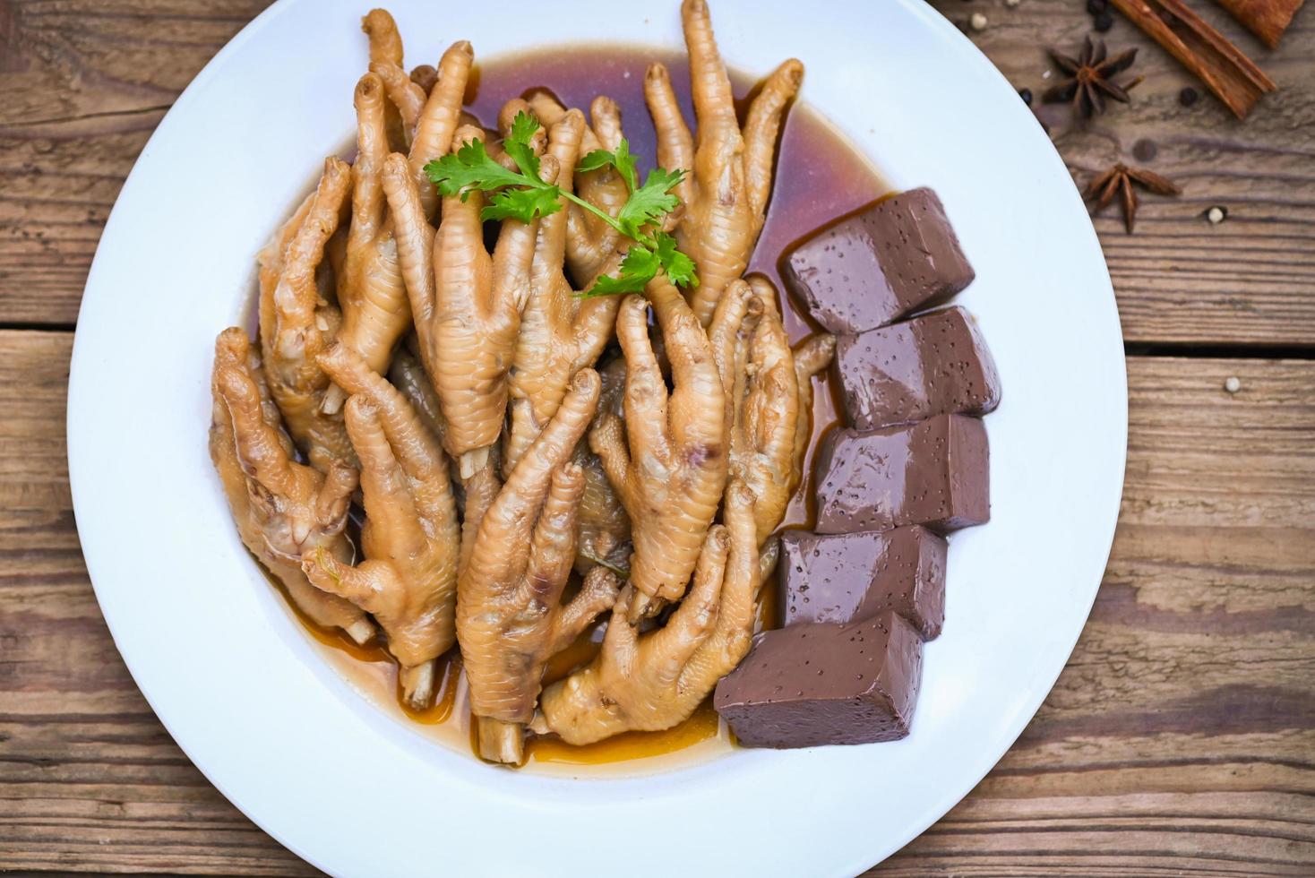 Cooking chicken feet foot stew on white with herbs and spices ingredients with chilli lemon vegetable on wooden background, Asian chinese food menu stew, Thai food, chicken feet soup stewed photo