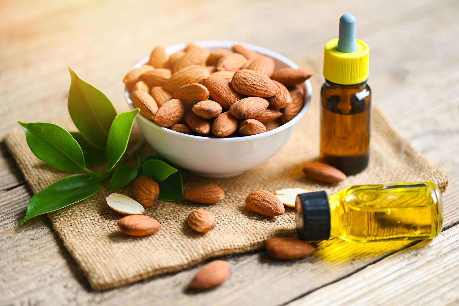 aceite de almendras y nueces de almendras en el bol, delicioso aceite de almendras dulces en botella de vidrio, nueces de almendras tostadas para alimentos saludables y aceites vegetales orgánicos para cocinar o spa foto