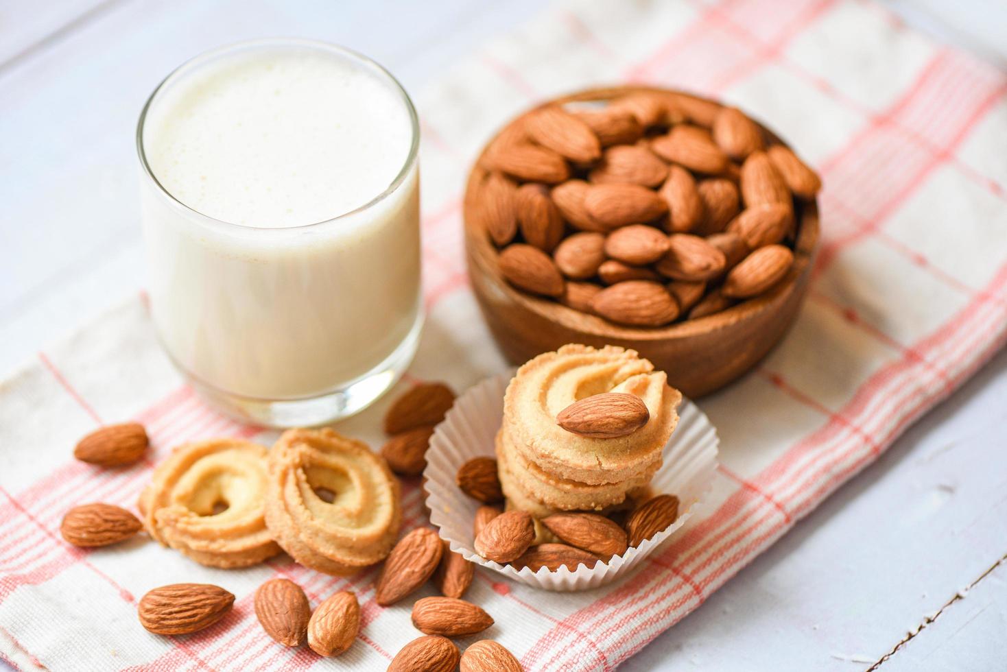 vaso de leche de almendras y galleta para el desayuno comida saludable - nueces de almendras sobre fondo de tazón de madera foto