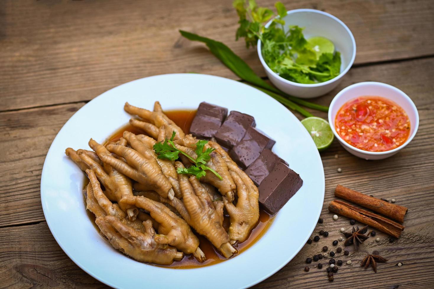 Cooking chicken feet foot stew on white with herbs and spices ingredients with chilli lemon vegetable on wooden background, Asian chinese food menu stew, Thai food, chicken feet soup stewed photo