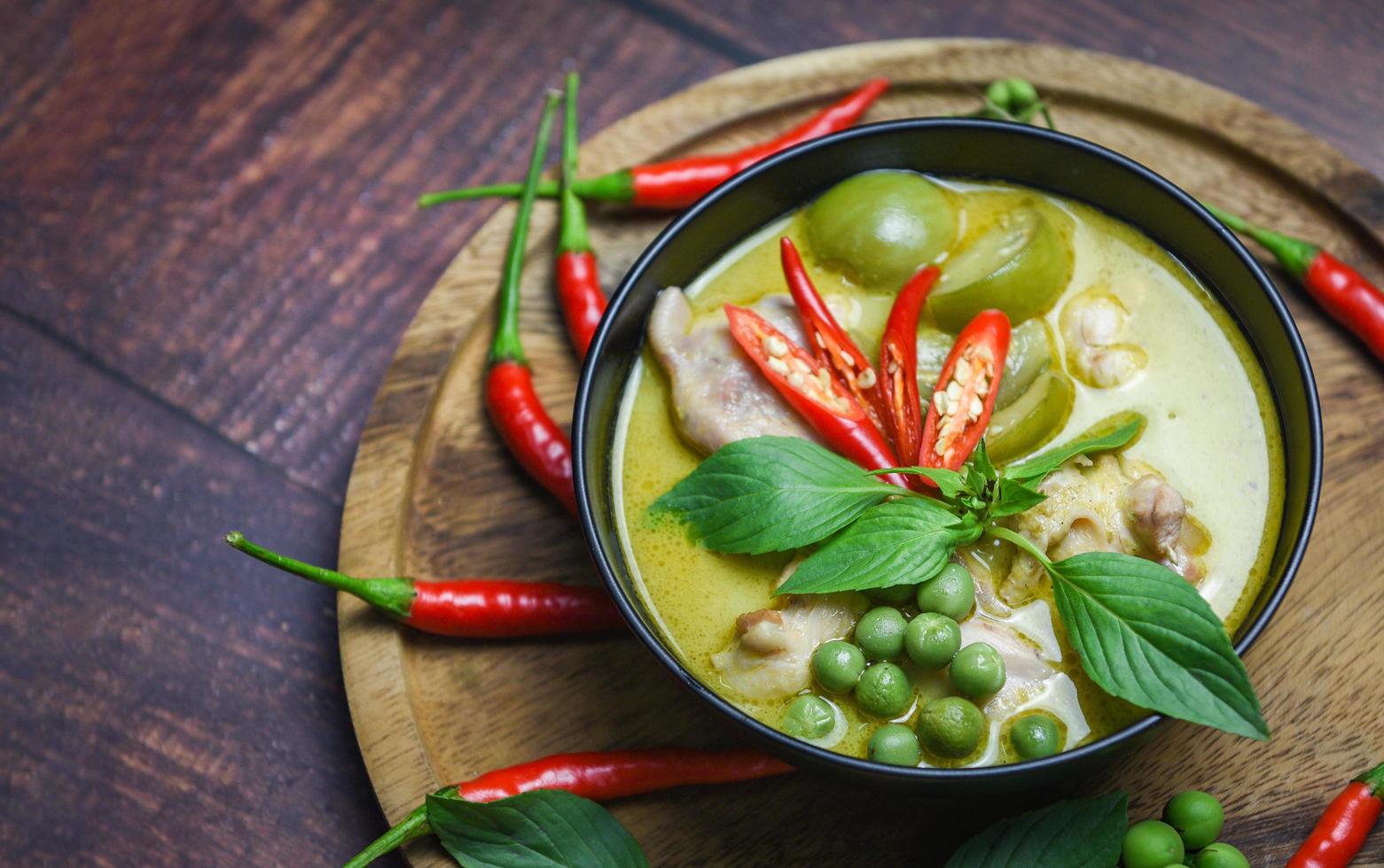 Thai food green curry on soup bowl with ingredient herb vegetable on wooden plate background - green curry chicken cuisine asian food on the table photo