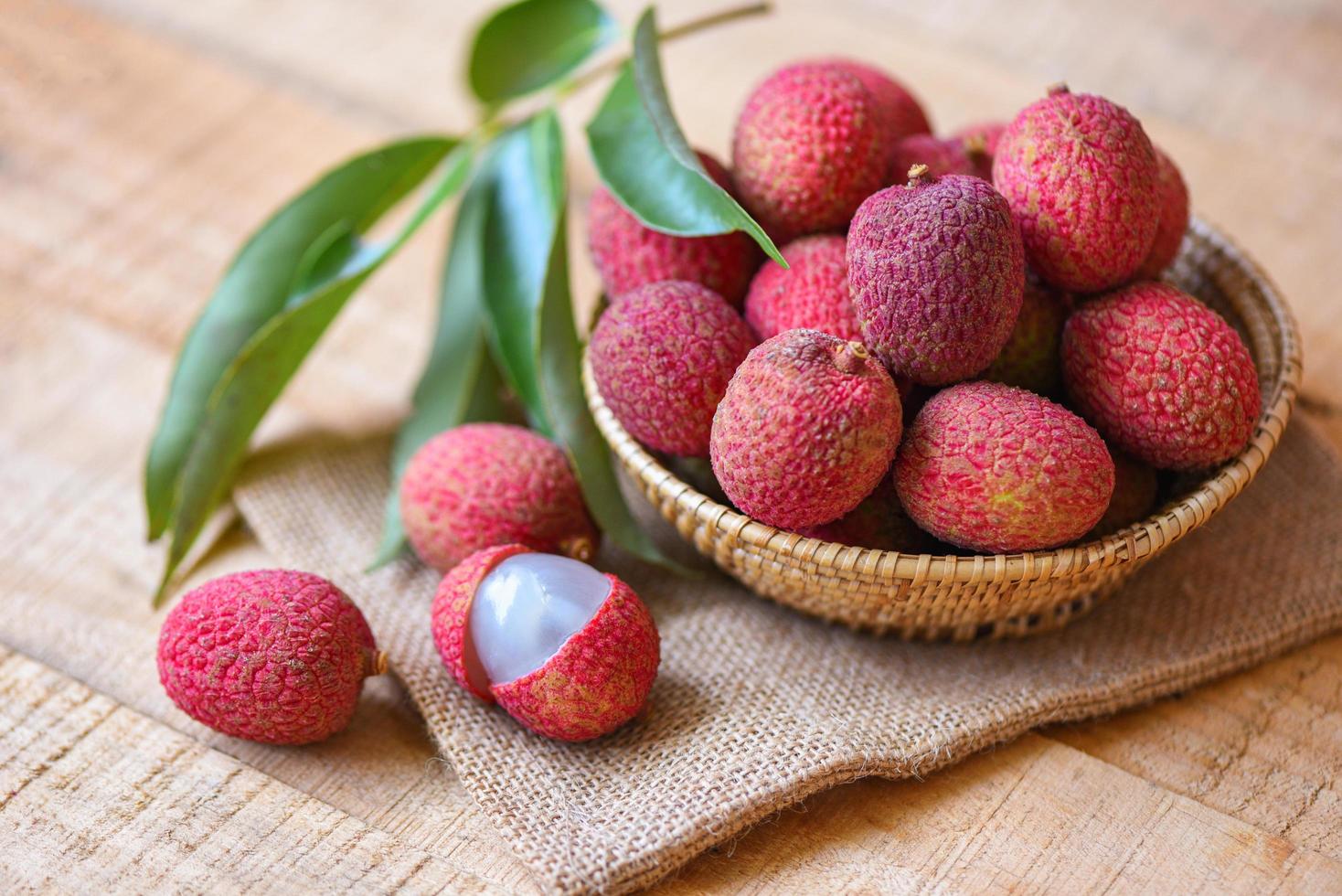 rebanada de lichi pelada en madera - lichi fresco con hojas verdes cosecha en canasta de árbol de frutas tropicales verano en tailandia foto