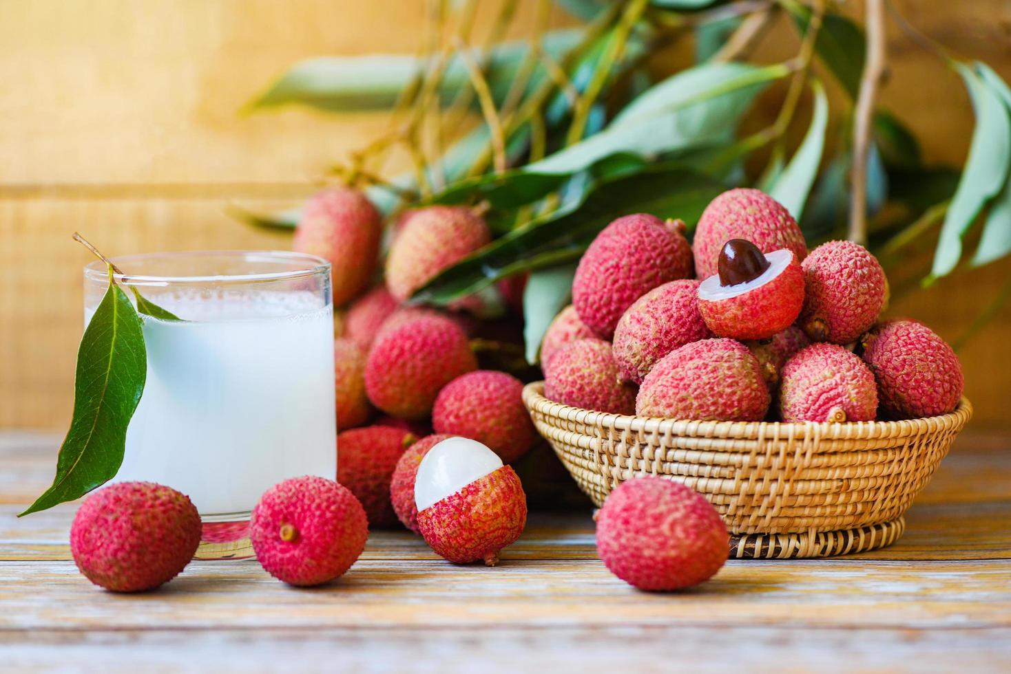 Lychee juice on wooden table - Fresh lychee drink and slice peeled with green leaves harvest in basket from tree tropical fruit summer in Thailand photo