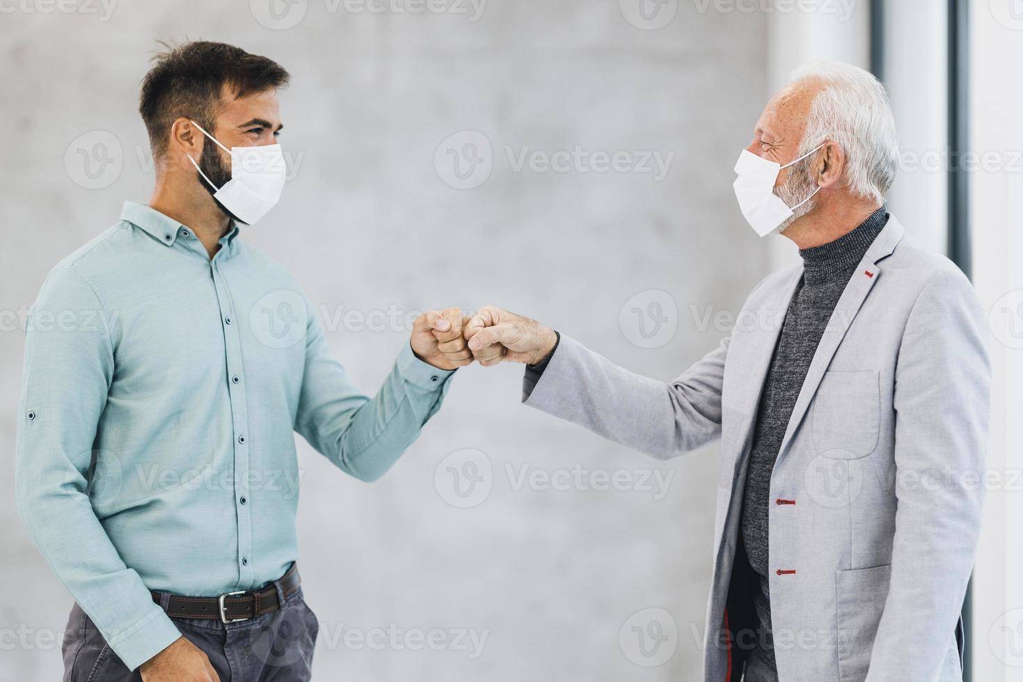 Two Business Man Greeting With Bumping Fists During Coronavirus Pandemic In The Office photo