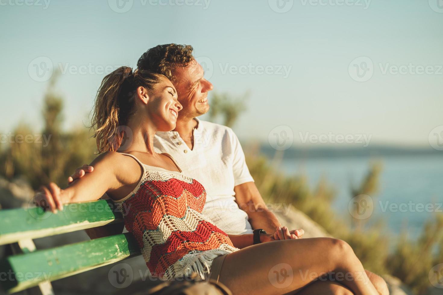 Couple Sitting On Bench And Enjoying Time On A Vacation Near The Beach photo