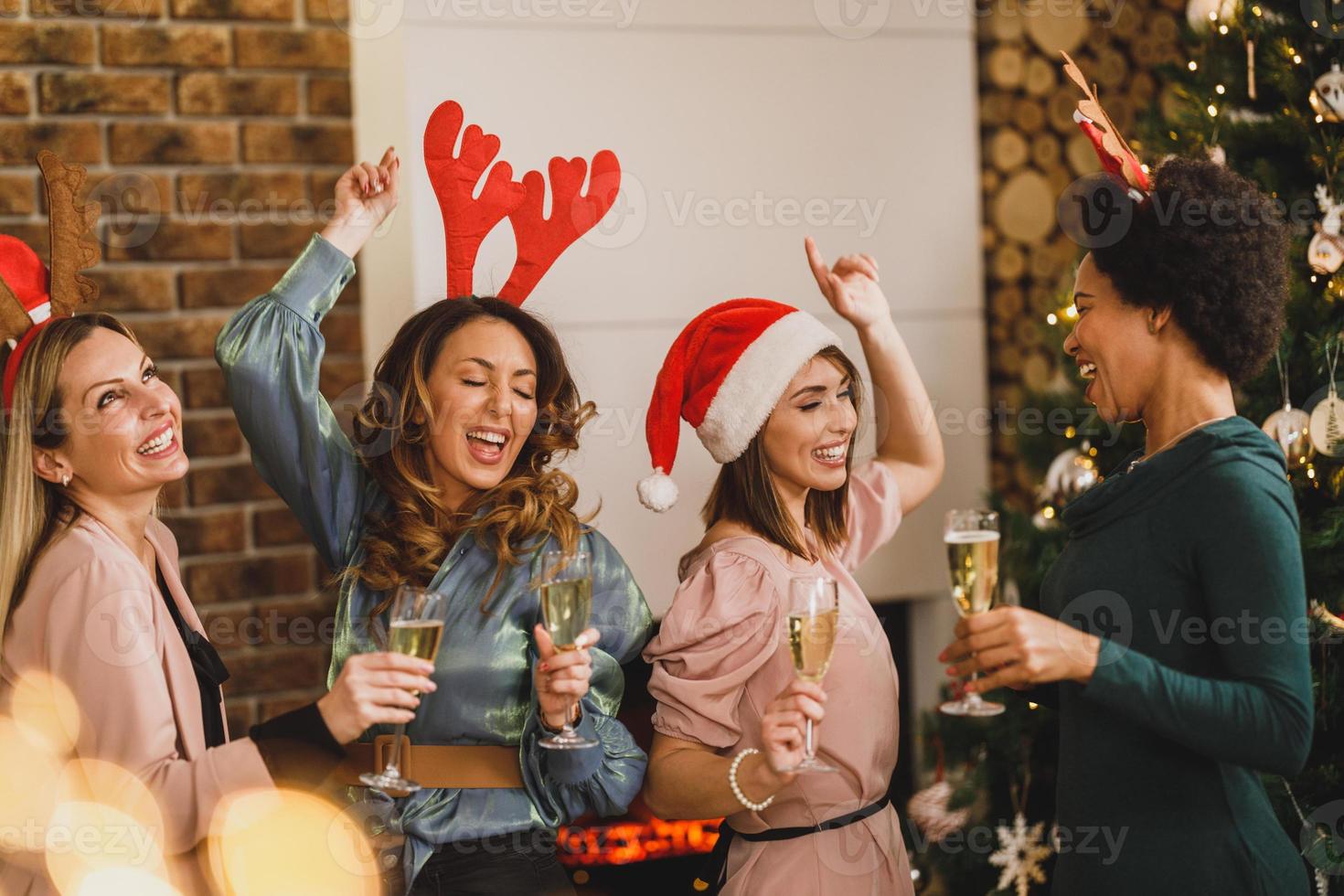 cuatro amigas multiétnicas divirtiéndose y bailando en casa fiesta de navidad foto