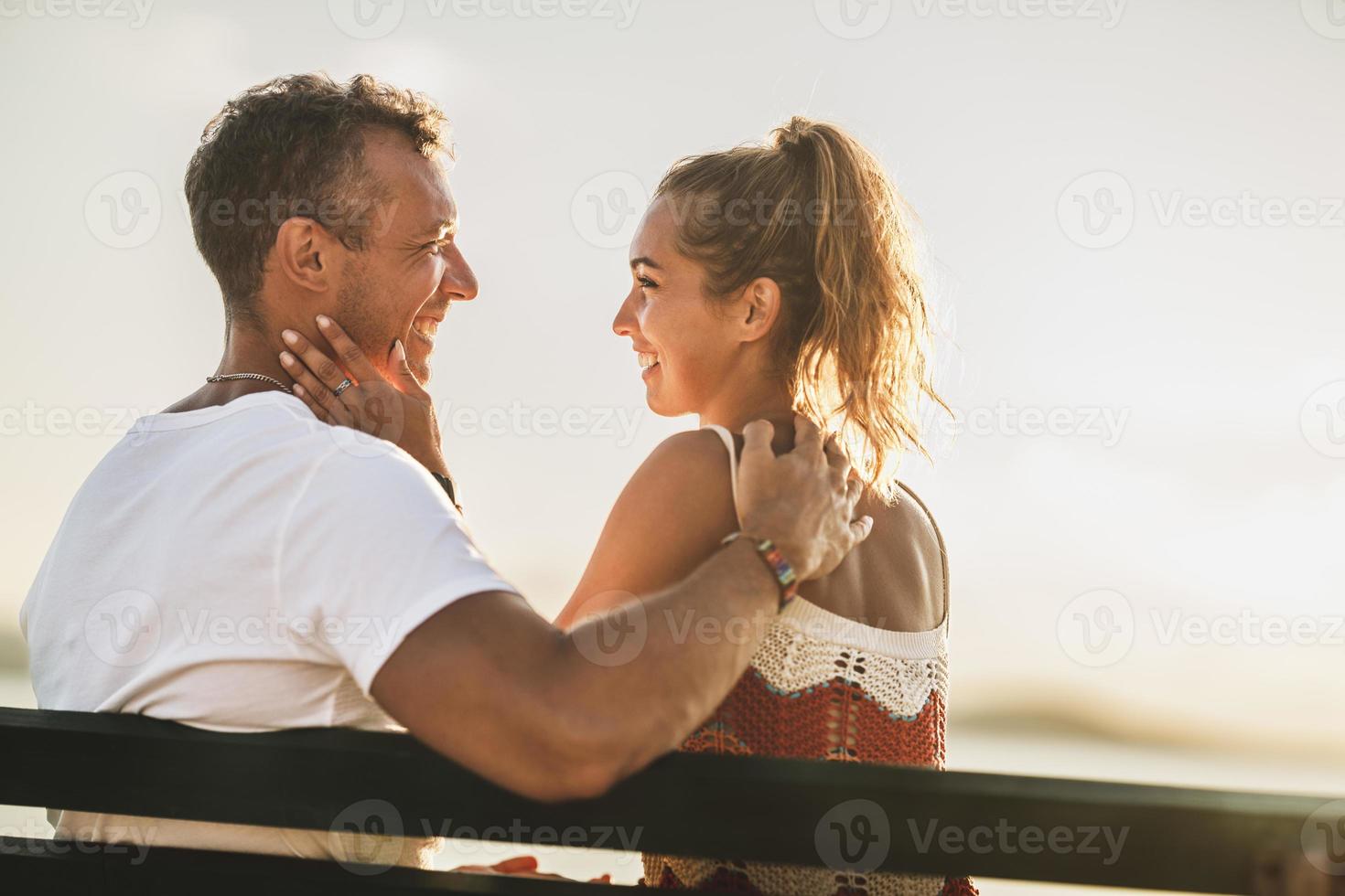Couple Sitting On Bench And Enjoying Time On A Vacation Near The Beach photo