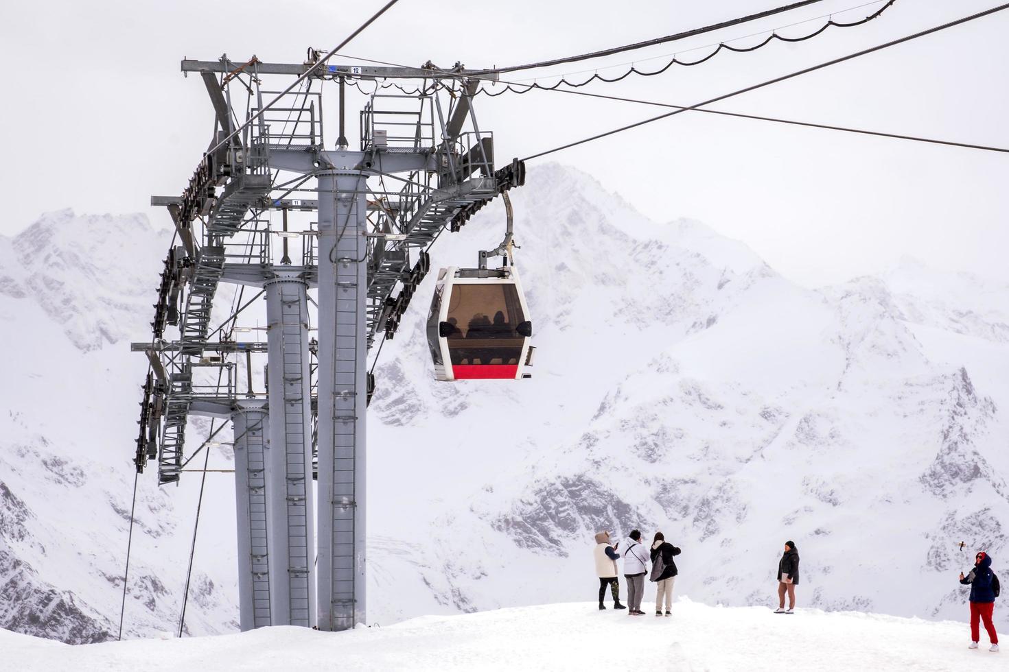 Elbrus National Park, Russia - October 13, 2022. Mountain snowy landscape with oprahs, alpine cable car cabins and tourists. photo