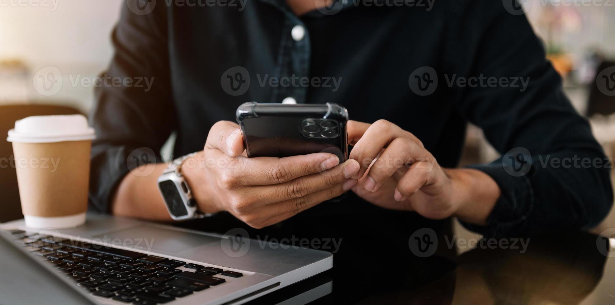 Woman hands is typing on a laptop and holding smartphone at office photo