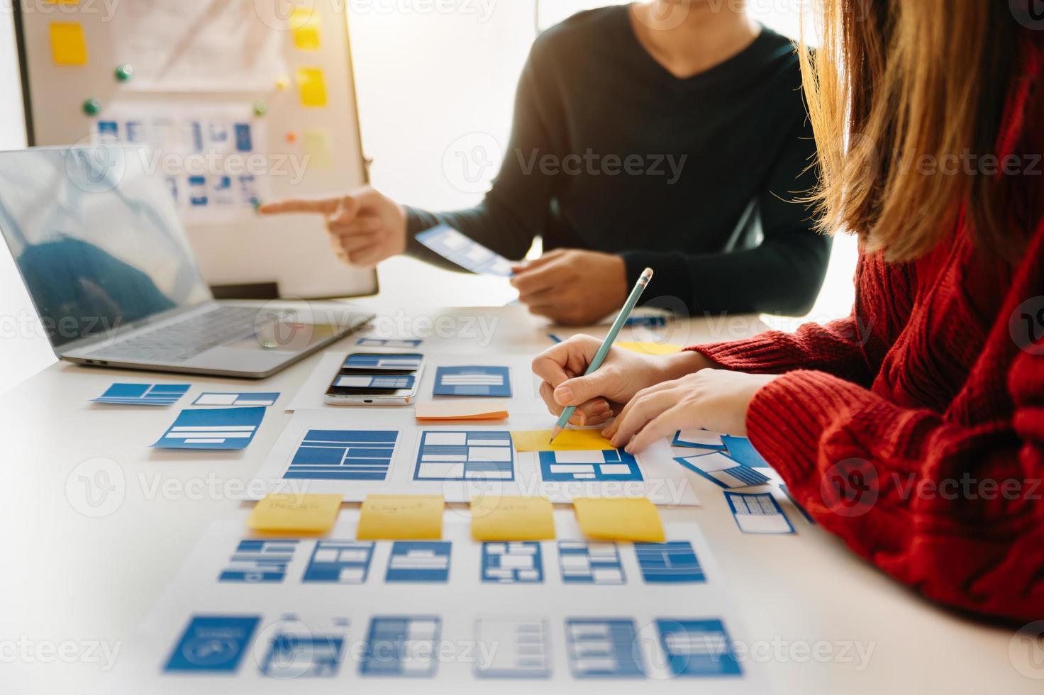 UX developer and ui designer brainstorming about mobile app interface wireframe design with customer breif and color code at modern office. photo