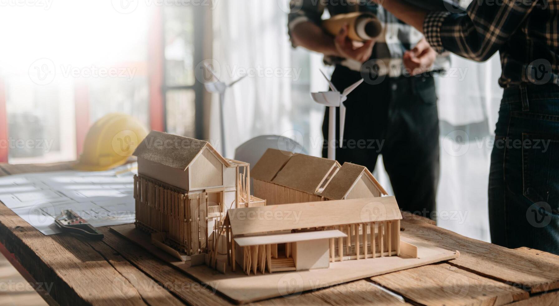 Professional team architect, engineer or interior reviewing blueprint on workplace desk behind house model in office photo