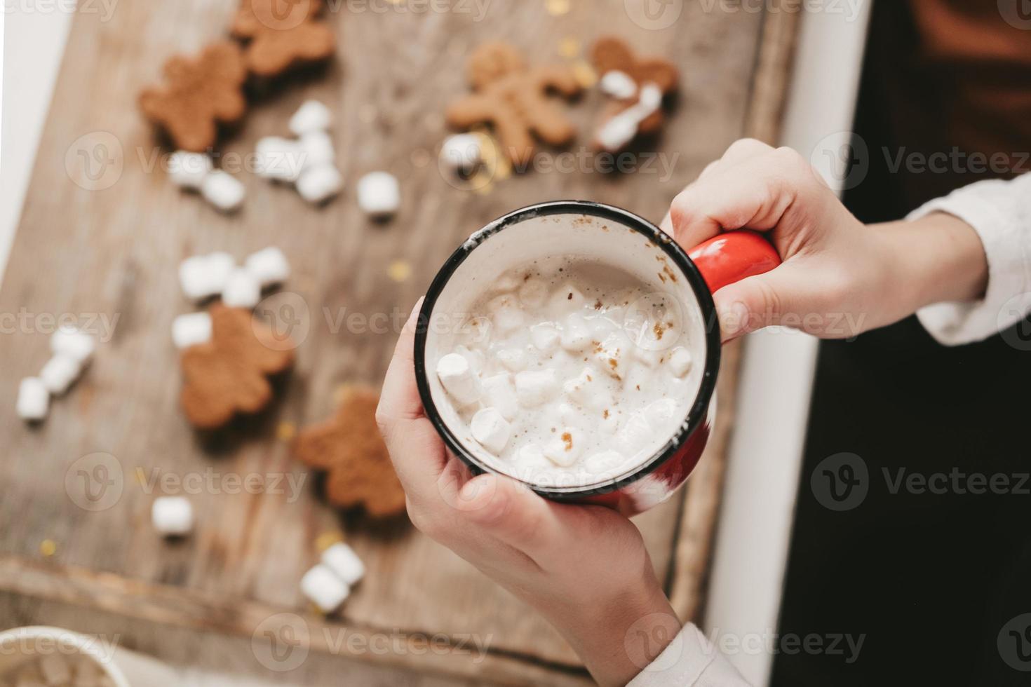 a cup of cocoa with marshmallows close-up, against the backdrop of Christmas cookies. Christmas sweets with cocoa and marshmallows for children on a wooden background. Winter vacation at home. photo