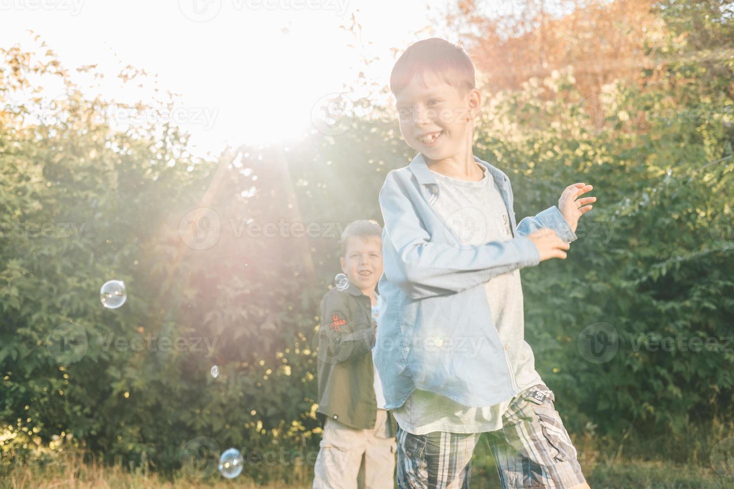 A boy is playing with soap bubbles in a summer park, Among the greenery. photo