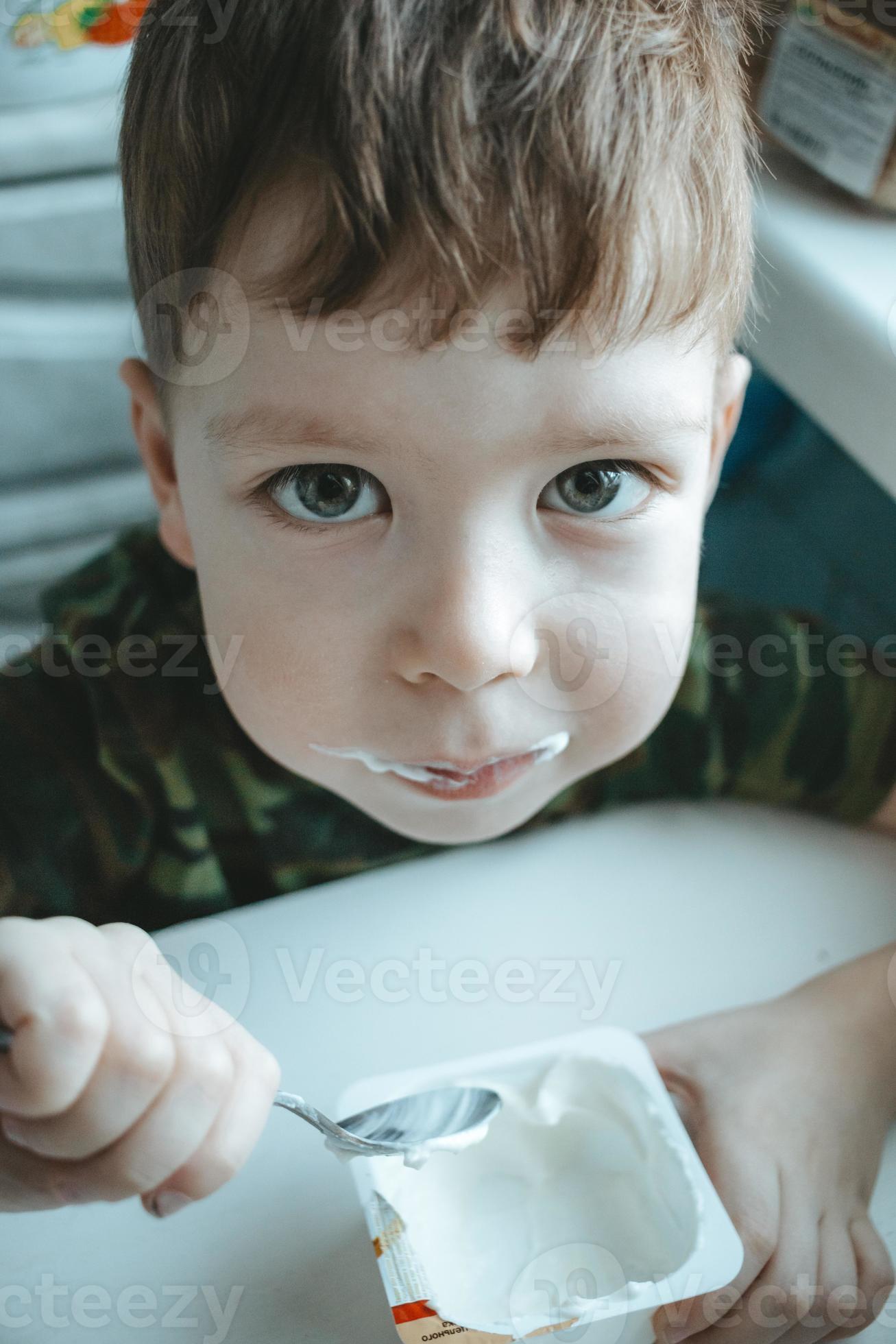 Cute little boy with big eyes eats yogurt with a spoon 14239004 Stock