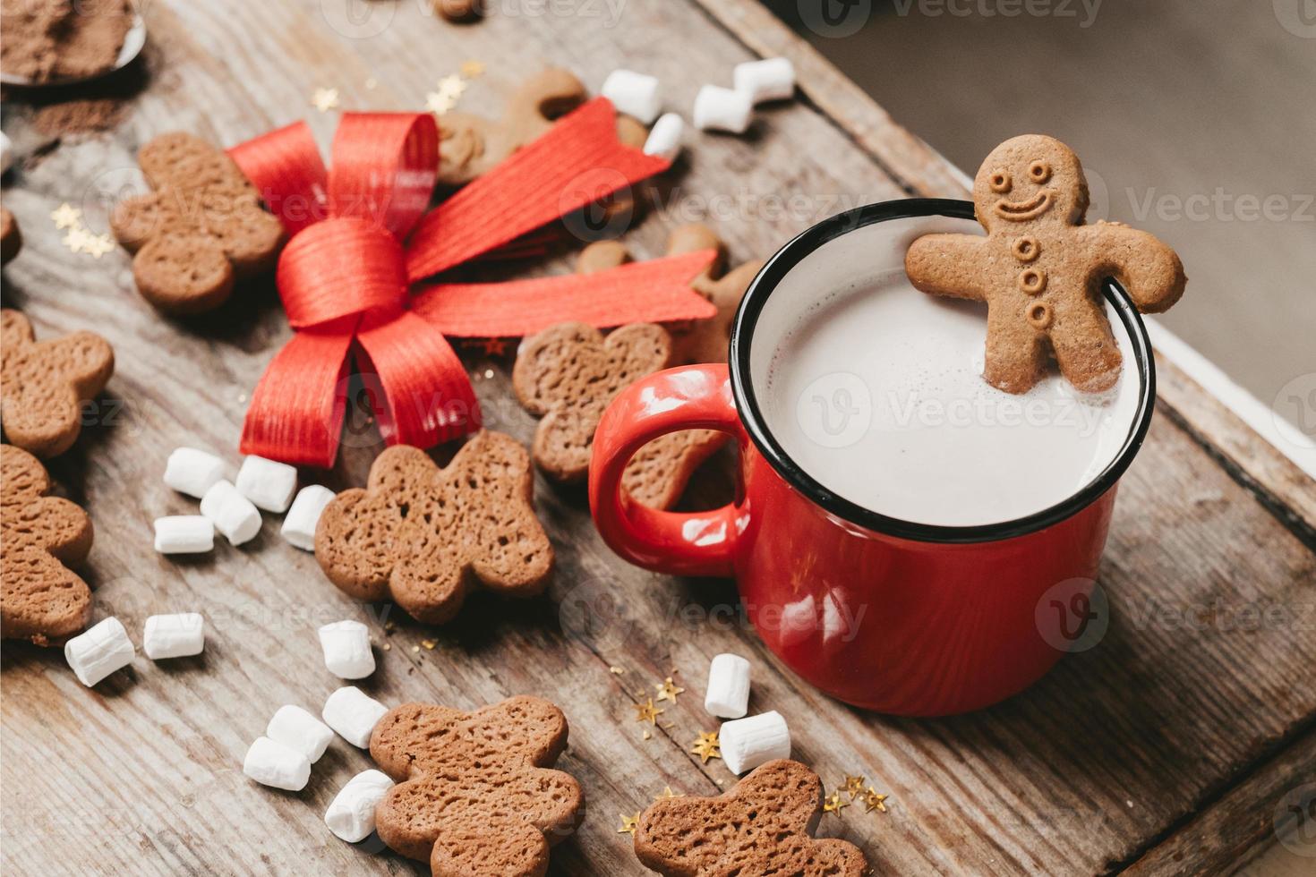 ginger man in a cup of cocoa with a big red bow on a wooden background, top view. Various Christmas sweets with a cup of cocoa on the table. Christmas flatlay photo