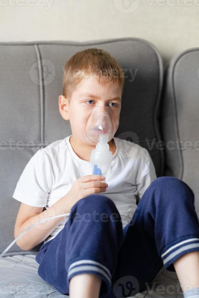 A little boy sits with an inhalation mask during cough and bronchitis photo