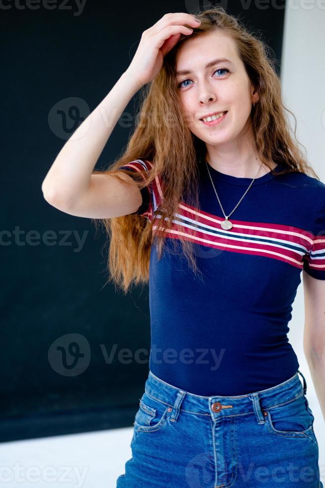 portrait of a young smiling girl, with long hair, in a tight T-shirt and jeans photo