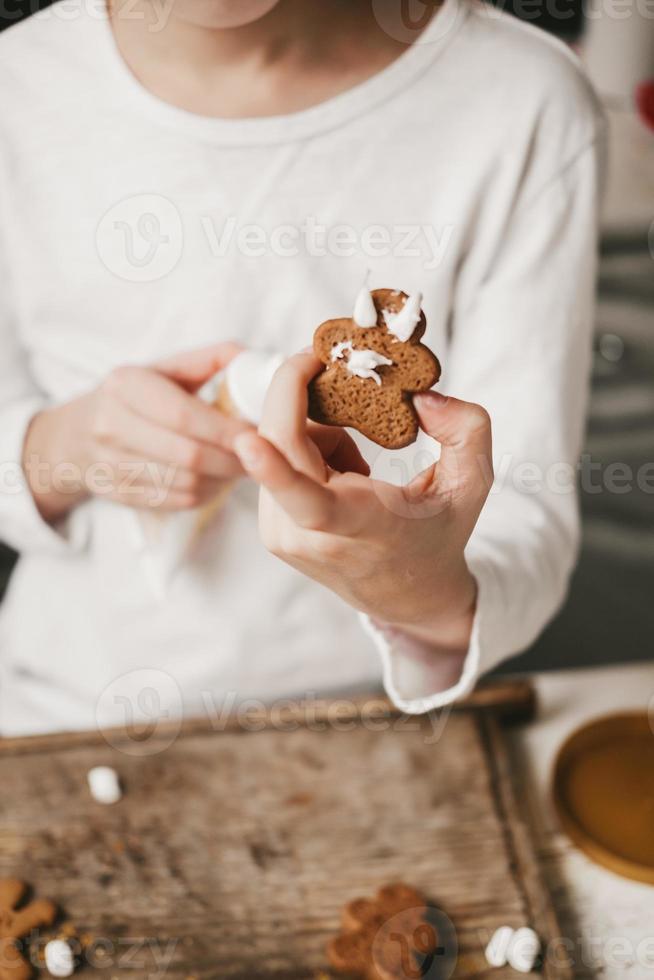 ginger man in white glaze in the hands of a child, close-up, on a white background. The gingerbread man is bathed in cocoa. Christmas mood. Christmas sweets and drinks, copy space photo