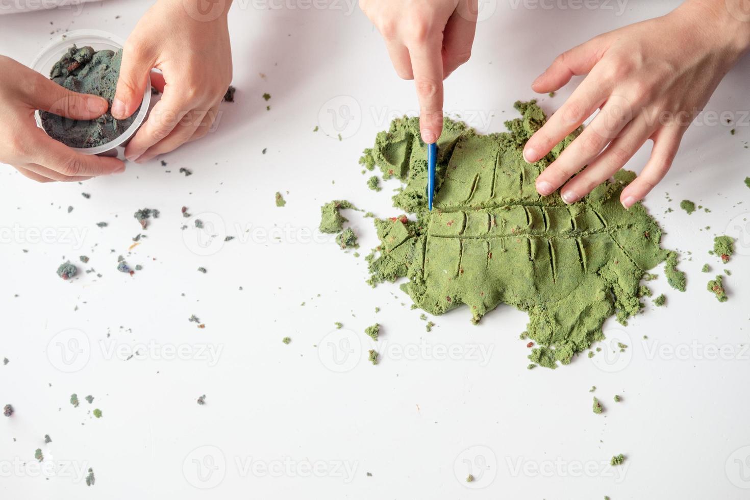 children play with Kinetic sand at home. Development of fine motor skills, top view photo