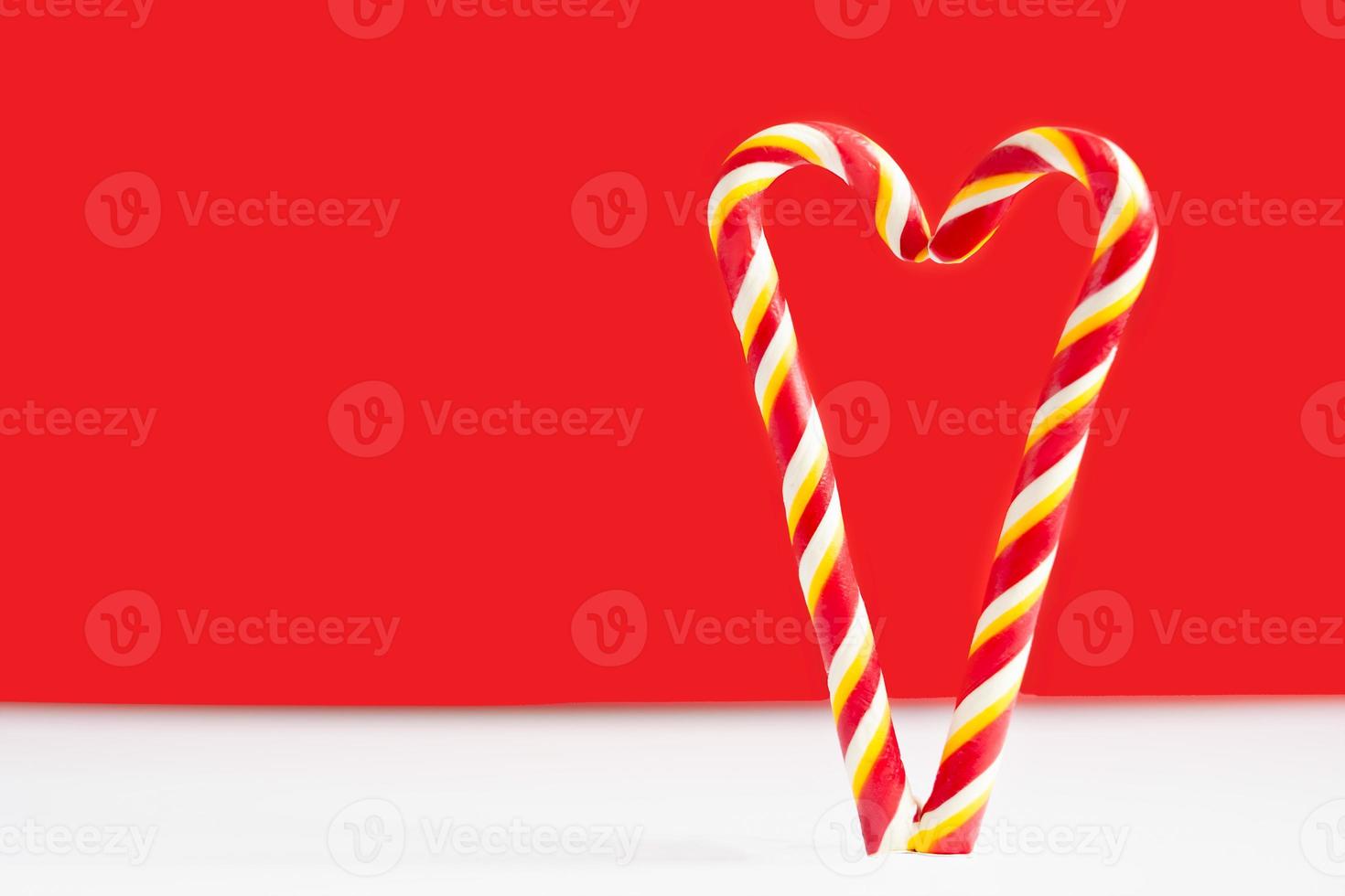 Christmas candy canes on a red background. Heart on a red background. Heart made of lollipops. Heart for valentine's day photo