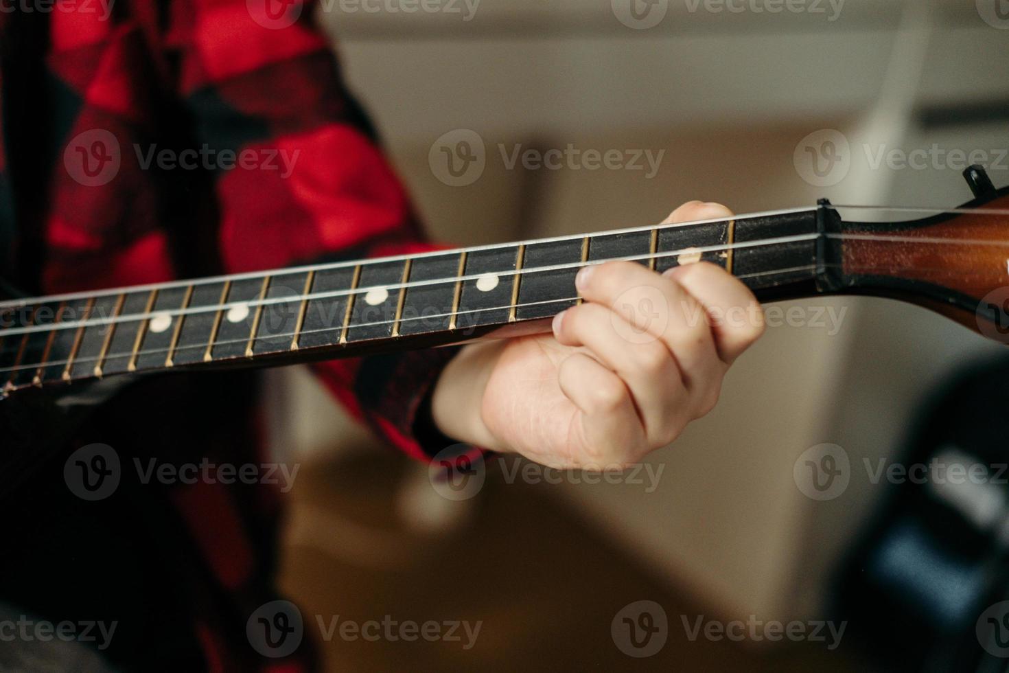 Close-up hands playing the guitar. Music lessons at home. Hobby for the soul. home teaching music. The boy plays a string instrument. photo