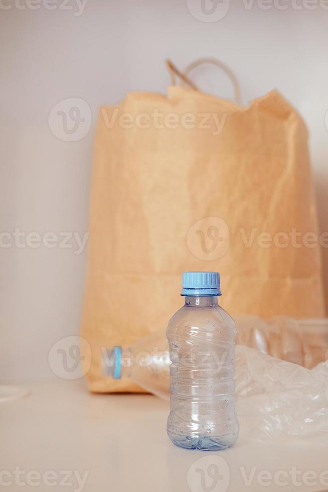 plastic bottle on the background of a paper bag. Plastic problem. Sorting garbage at home. The global problem of ecology photo