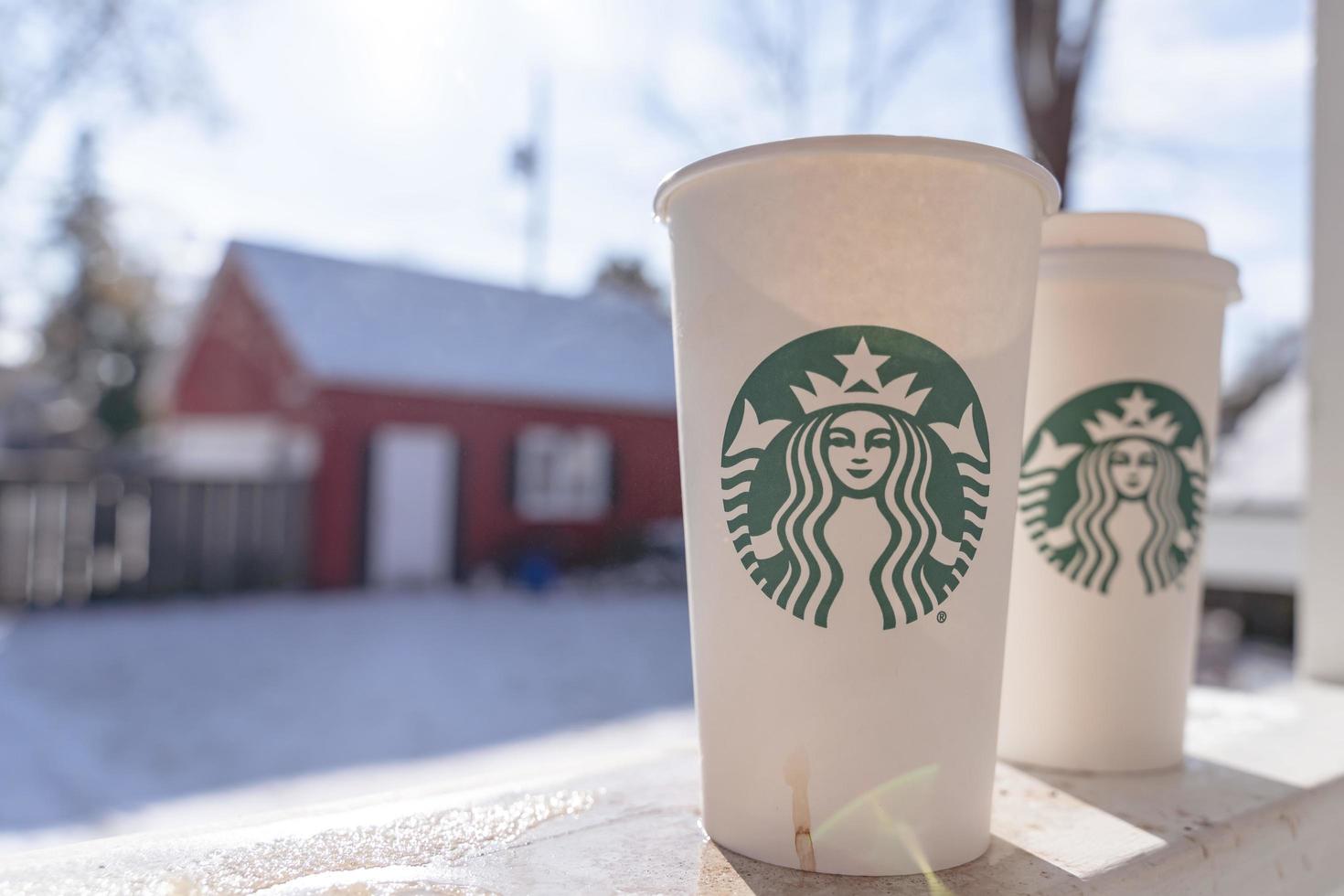 Marinette,WI,USA - Nov10, 2022- Cups of Starbucks Hot Coffee put on white snow in winter garden, fresh and hot beverage take away concept.Starbucks Cafe Coffee Shop. photo