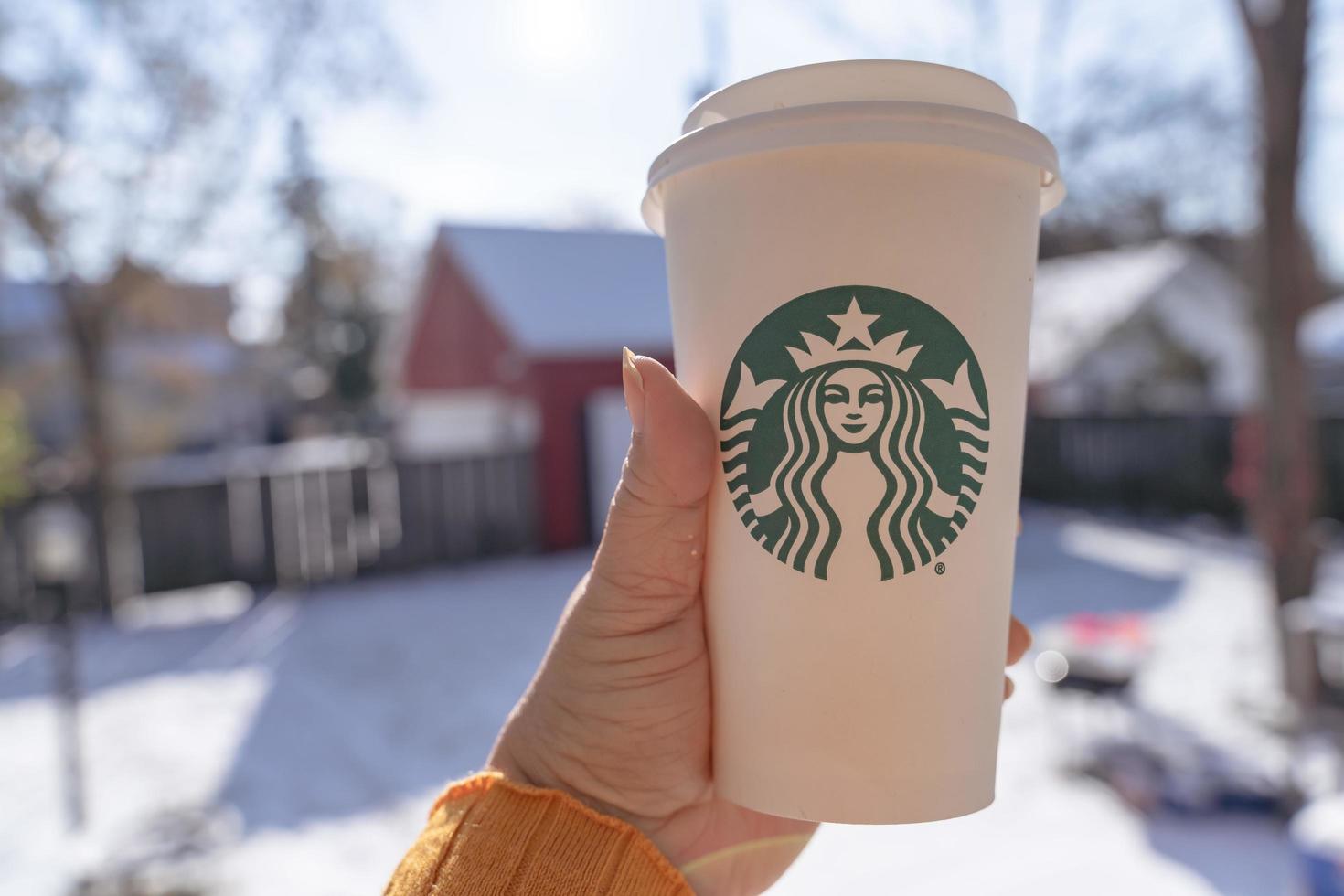 Marinette,WI,USA - Nov14, 2019- Cups of Starbucks Hot Coffee put on white snow in winter garden, fresh and hot beverage take away concept.Starbucks Cafe Coffee Shop. photo