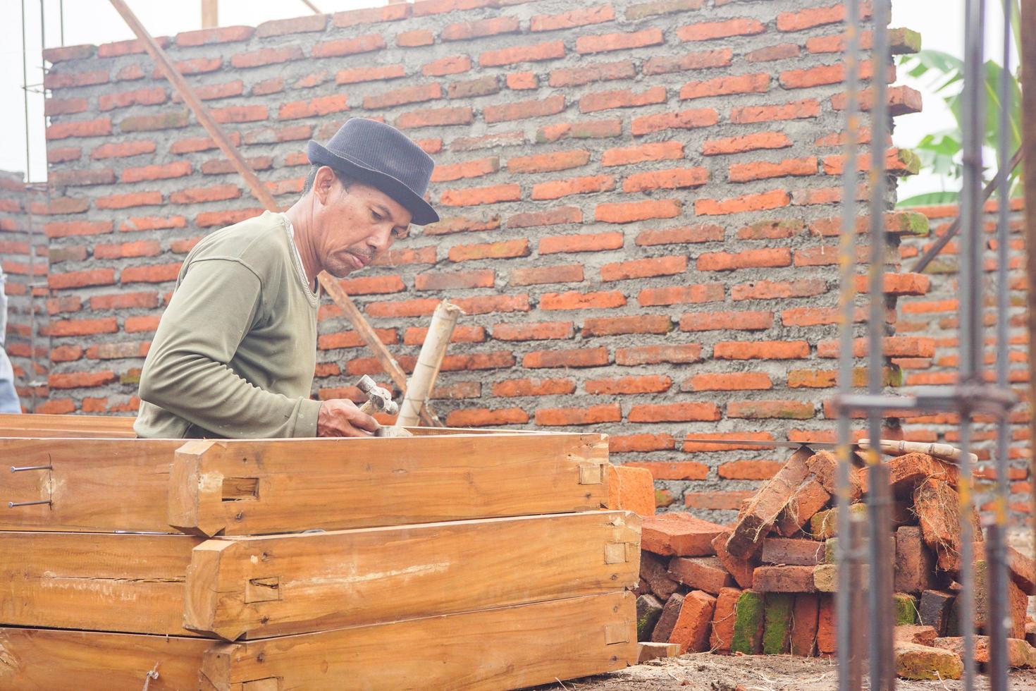 Tegal, Jawa Tengah, 2022 - construction worker taking measurements and hammering to mark on wooden door photo