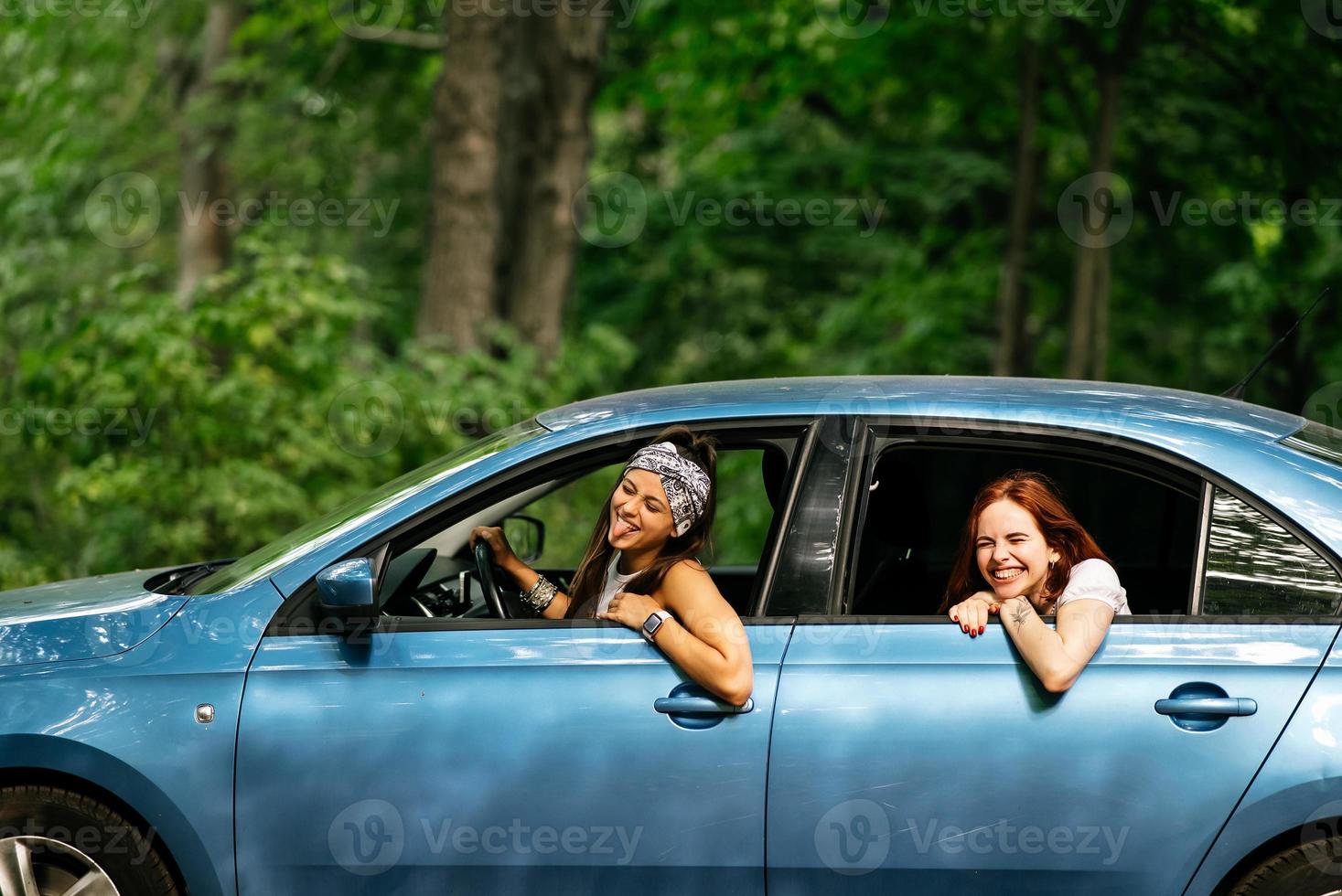 Two girlfriends fool around and laughing together in a car photo