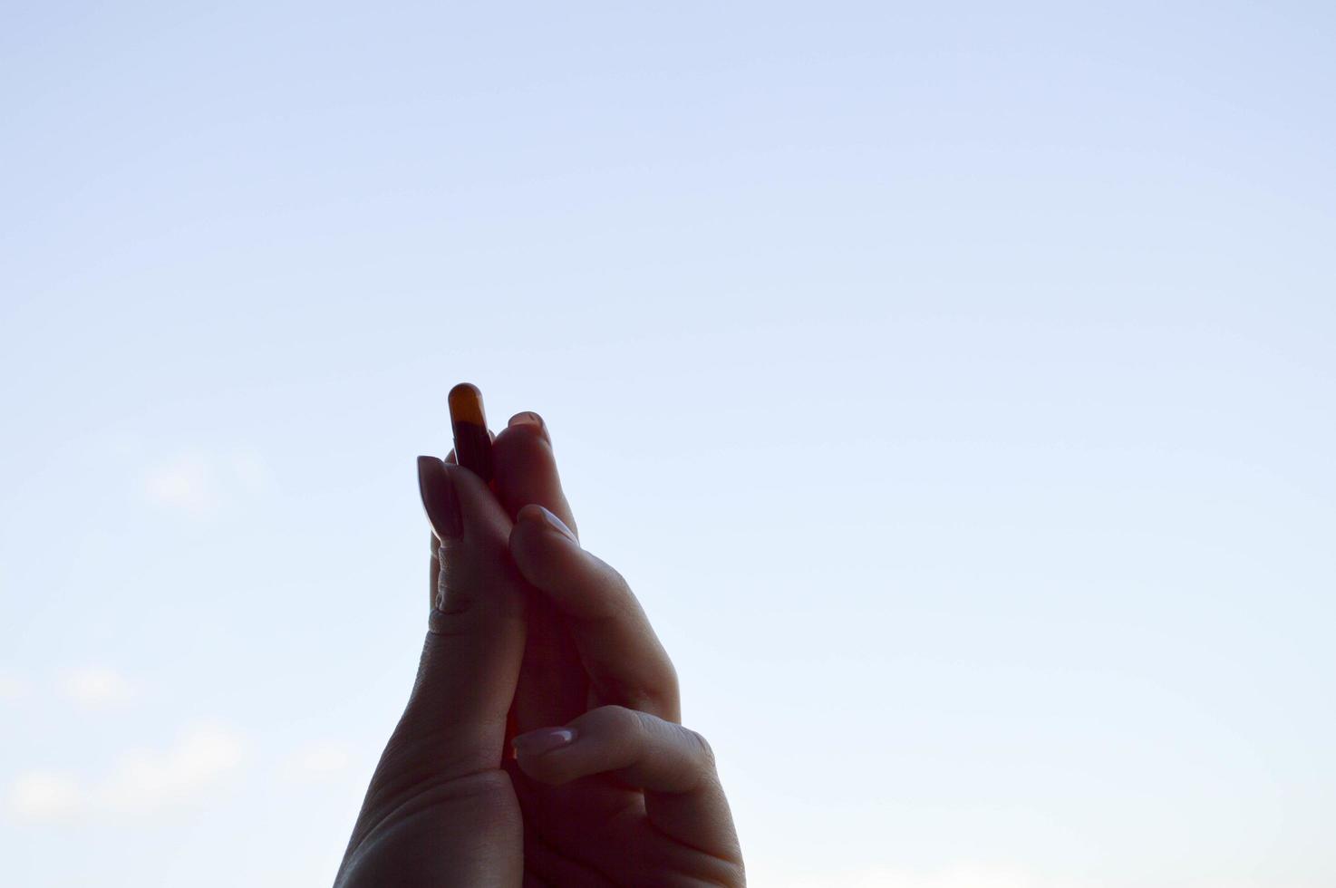 hermosa mano femenina sostiene una cápsula de píldora farmacéutica médica del coronavirus covid-19 para el tratamiento de enfermedades y virus en un fondo azul del cielo foto